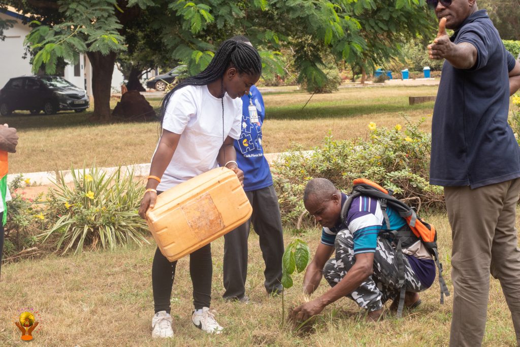 Young participants plant and water a sapling together.